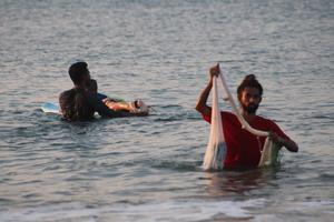 le pecheur jette le filet prés des surfeurs